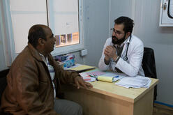 Abu Raed; an asthma patient, visits Dr. Mohammad Al-Omari at IRC's health clinic in Za'atari refugee camp. Dr. Mohammad does a check-up and gives him health advice.