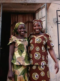 Ruth stands with her mother outside their home in Yola.