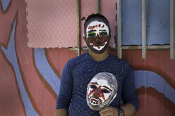 A young Syrian refugee wears and carries masks he painted at an IRC workshop 