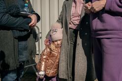 A young girl standing next to a woman, who has her arm around the girl