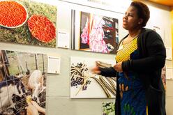 African women stands in front of photos of food and livestock