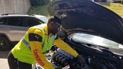 Norbert works on a car at his auto shop in Stone Mountain. He is wearing a sweater that has "Cameroon" printed on the sleeve.