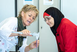 A woman demonstrates the use of a tool for a student 