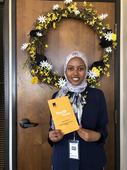 IRC in Dallas' 2019 Mayors Intern Rahmo Bare holds a copy of Youth Voices