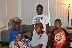 Resettled family sitting on a couch and chairs in the living room. 