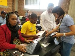 Group of adult students at a technology workshop with computers and phones.