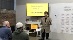 IRC staff member teaching a class, jeopardy game on the screen.