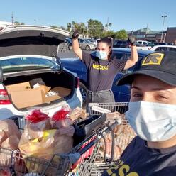 Two IRC staff members wearing face masks with shopping carts full of grocery bags.