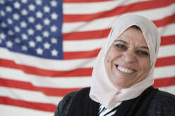 Woman smiling for a photo in front of the American flag.
