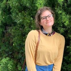 Census Educator Volunteer Caitlin Silianoff posing in front of a bush.