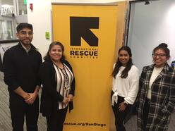Four people at the DACA workshop smiling for a picture in front of an IRC banner.