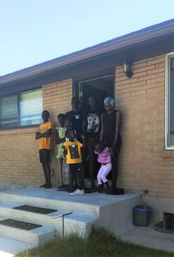 Refugee family standing at the front door of a home.