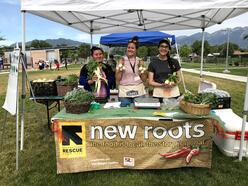 The New Roots farmers holding produce in a market tent.