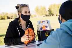 Employee sitting with client handing them a orange education pack.