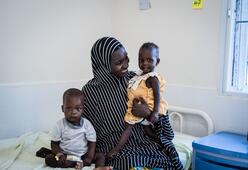 A mother sits on a hospital bed with her two young children in the Nigeria health center where they were being treated for acute malnutrition,