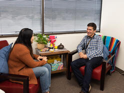 A man and woman smile while sitting across from each other.