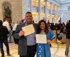 Fabian and Patricia, journalists from Venezuela, smile and pose with their naturalization papers at the Utah Capitol