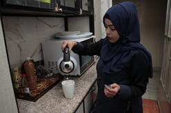 Dr. Bushra pours coffee into a mug.