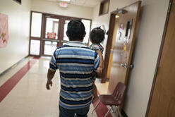 A man holding a small child walk the Welcome Center hallways.