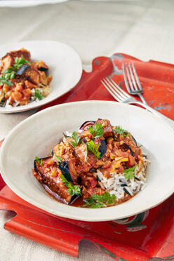 Chef Shanthini’s fried eggplant curry in a white dish on a red placemat. 