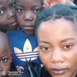 A close up selfie of Mauwa with three of her children, all looking at the camera 