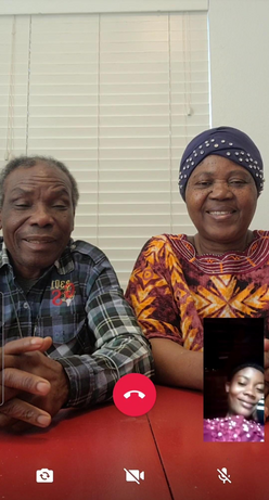 A screenshot of a smart phone, with Patrice and his wife sitting at a table and their daughter Mauwa in a small box on the lower right side of the screen