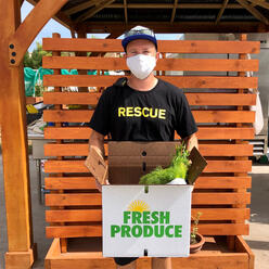 Isaac, an IRC staff member, holds a Fresh Produce Box. 