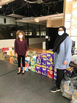 2 MCC volunteers stand next to stacked boxes of diapers to donate to families in need