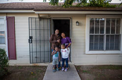 Congolese refugees Robert and Esther pose for a photo with their two young children at the front door of their home in Phoenix.