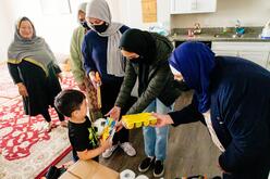 Three women hand gifts to a young boy, with two other women smiling in the background.