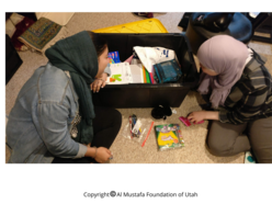 Two children are looking at the gifts they received for Eid al Fitr thorugh the Al-Mustafa Foundation