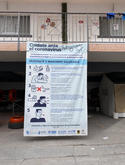 Una pancarta en español que promueve la prevención del COVID-19, colgada de una barandilla en el segundo piso de un antiguo motel que funciona como un "hotel de triaje" respaldado por el IRC en México. 