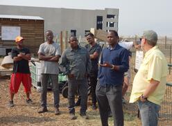 Members of the board of directors of Utah Refugee Goats (URG) stand outside at the ranch, in the middle of a discussion