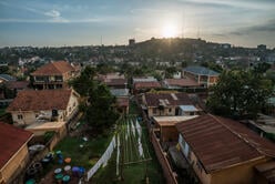 A photo of a landscape during a sunny afternoon in Kampala, Uganda. There are houses and green hills. 