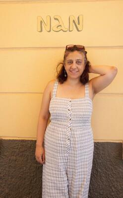 A woman stands against a wall that reads, "Nan."