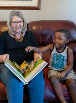 An IRC volunteer in Phoenix reads from a book as a child looks on.