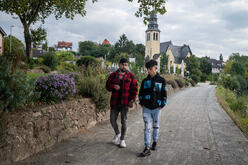 Afghan refugee brothers Ali, 17, and Mehdi, 29, talk as they walk along a river path in Germany.