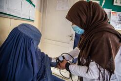 A woman in a burqa has her blood pressure taken by a health care worker in an IRC-supported clinic.