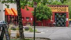 Street view of a red coffee shop and entrance into the parking lot. 
