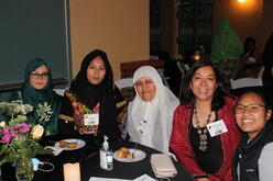 Women participants from the We Can Do It program sitting at a table at the IRC in Denver's Welcome Home fundraiser. 