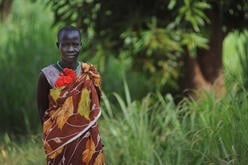 A woman in rural Central Equatoria state, South Sudan standing in tall grass.