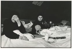 Two Bosnian women lie in beds in a refugee camp in Croatia, one of whom is crying.