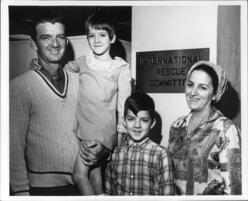 A Cuban family of four poses for a picture in front of a small sign that reads "International Rescue Committee"