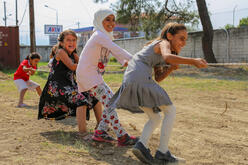 Syrian children living in a refugee camp in Greece play tug of war
