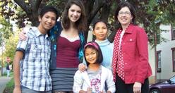 A refugee mother and her two children stands side-by-side with an American mother and her daughter