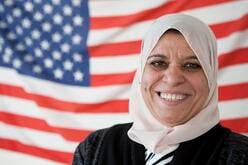 Donna Alberico Bushra smiling for a picture in front of the American Flag.