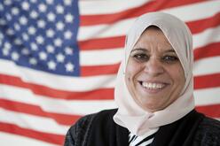 Donna Alberico Bushra smiling for a picture in front of the American Flag.