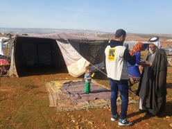 An IRC aid worker speaks with a man whose family has been displaced in Syrias Idlib province