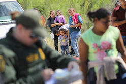 Central American asylum seekers wait as U.S. Border Patrol agents take groups of them into custody near McAllen, Texas.
