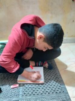 Mounzer sits on the floor and draws.
